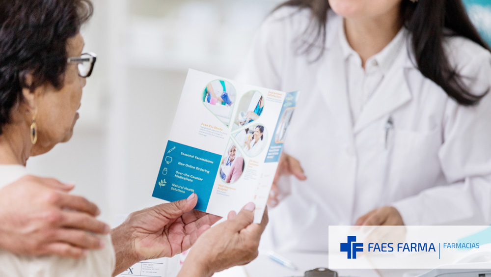 Farmacéutica que está realizando una intervención de educación sanitaria explica un folleto a una paciente.