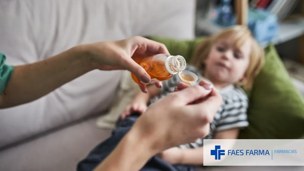 Madre dando jarabe natural que ha adquirido en la farmacia a su hijo pequeño.